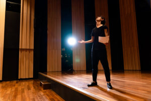 man in theatre stage holding a light