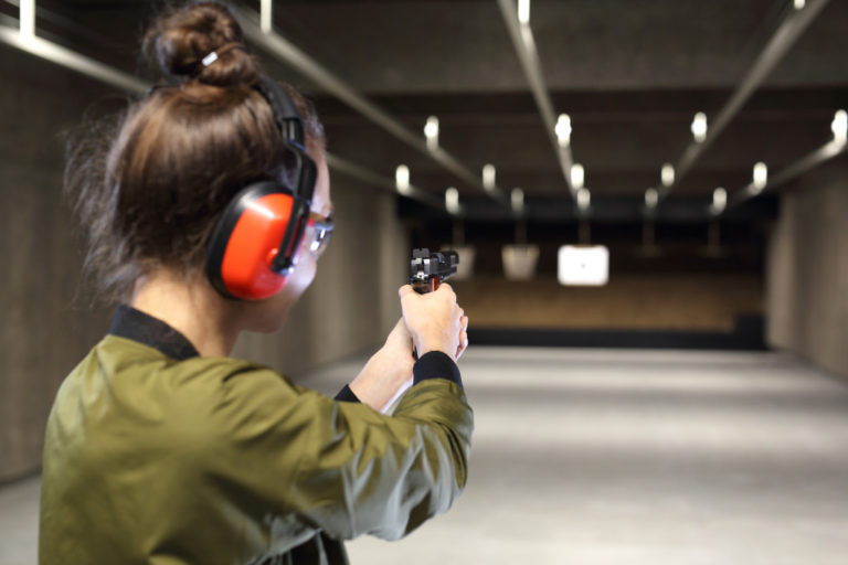 woman shooting a pistol inside an indoor shooting range