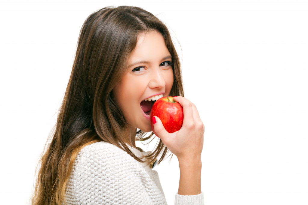 Young woman eating an apple isolated on white