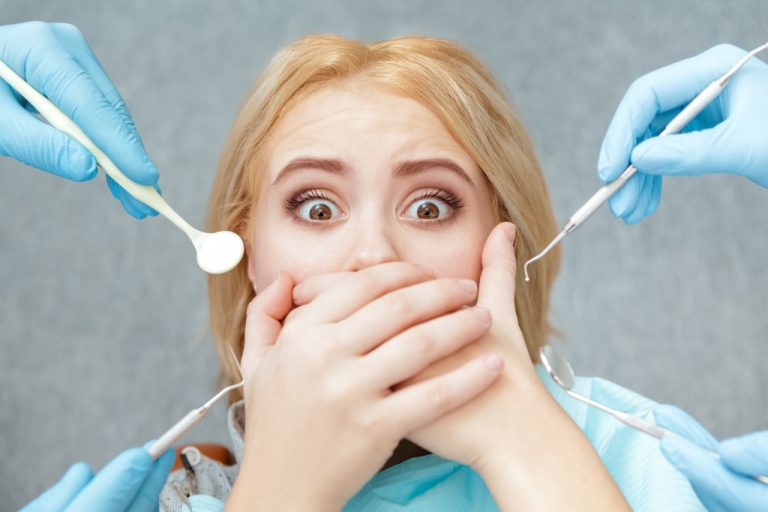 Woman afraid and covering her mouth from the dentist