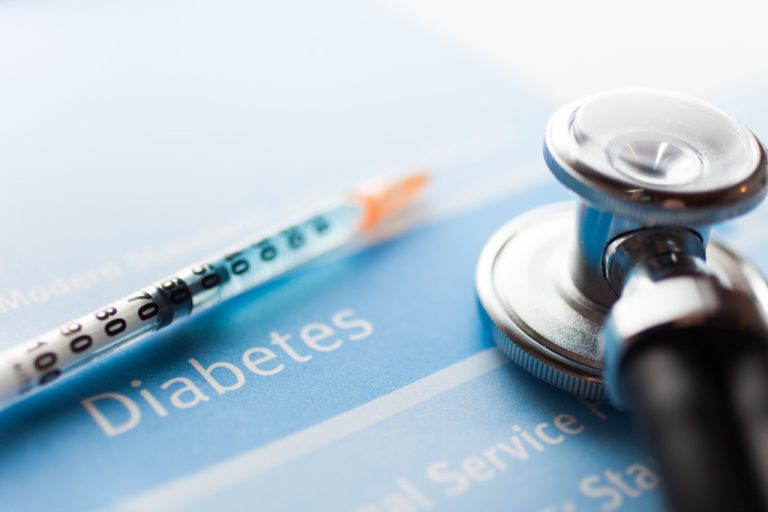closeup on a diabetes document with syringe and stethoscope