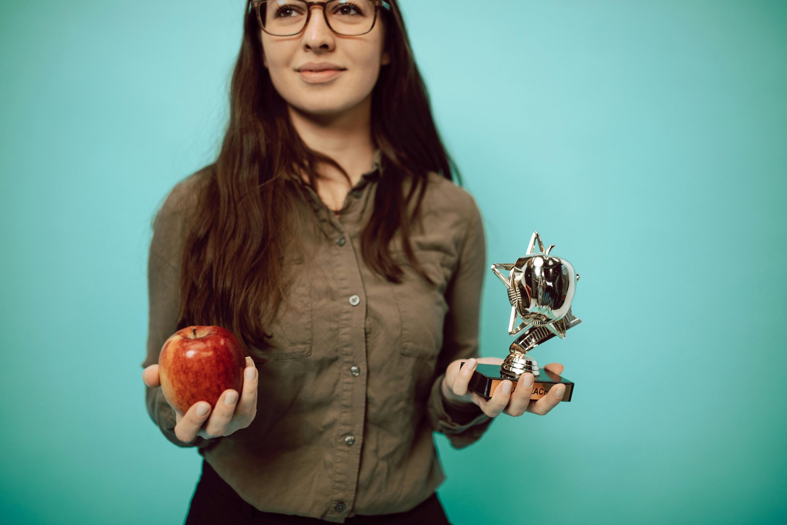 employee smiling while holding a trophy and an apple